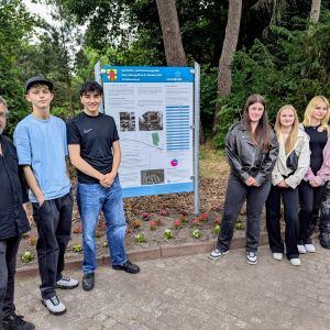 Klasse BI-TVM-1A und Herrn Baumann vor Geschichts- und Erinnerungstafel auf dem Friedhof Bungerhof in Delmenhorst