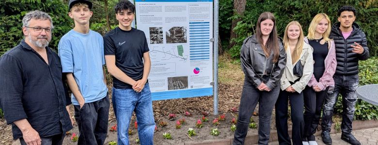 Klasse BI-TVM-1A und Herrn Baumann vor Geschichts- und Erinnerungstafel auf dem Friedhof Bungerhof in Delmenhorst