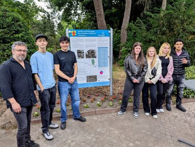 Klasse BI-TVM-1A und Herrn Baumann vor Geschichts- und Erinnerungstafel auf dem Friedhof Bungerhof in Delmenhorst